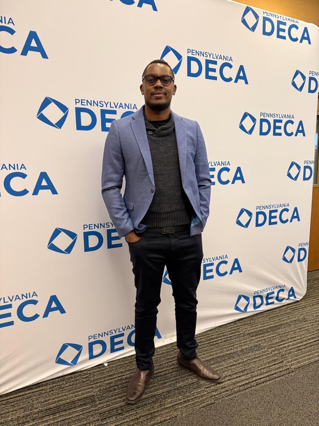 Morris Kithinji in front of the Pennsylvania DECA backdrop